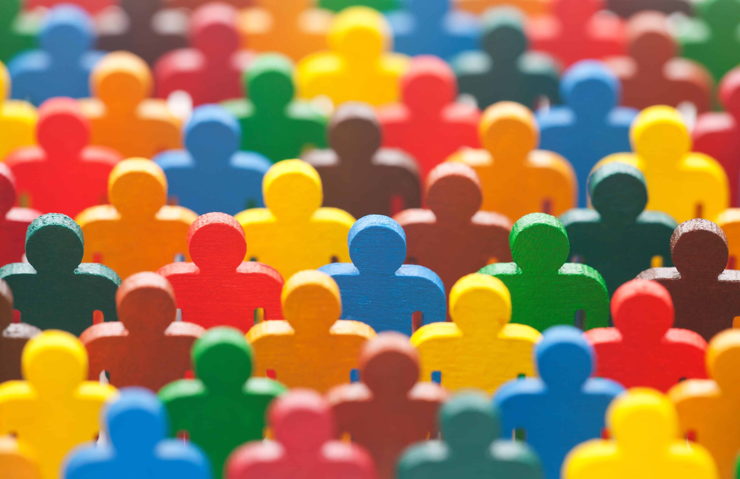 Many colorful plastic human figurines standing next to each other